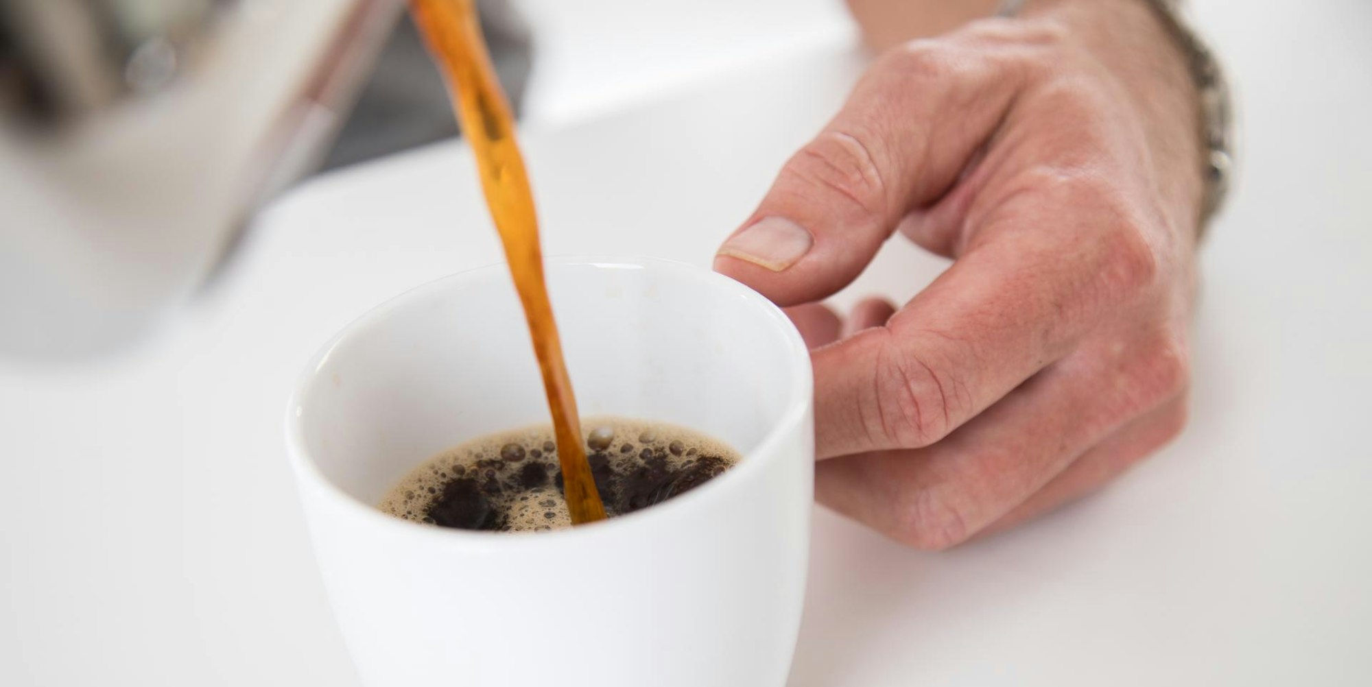 Jemand schüttet sich eine Tasse Kaffee ein