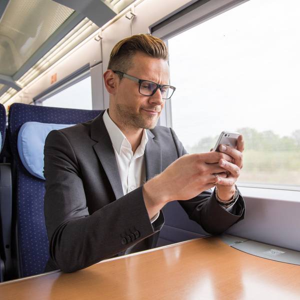 Mann sitzt mit Handy im ICE und sucht nach dem Handyempfang