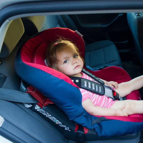 Kleinkind sitzt in einem Autokindersitz.
