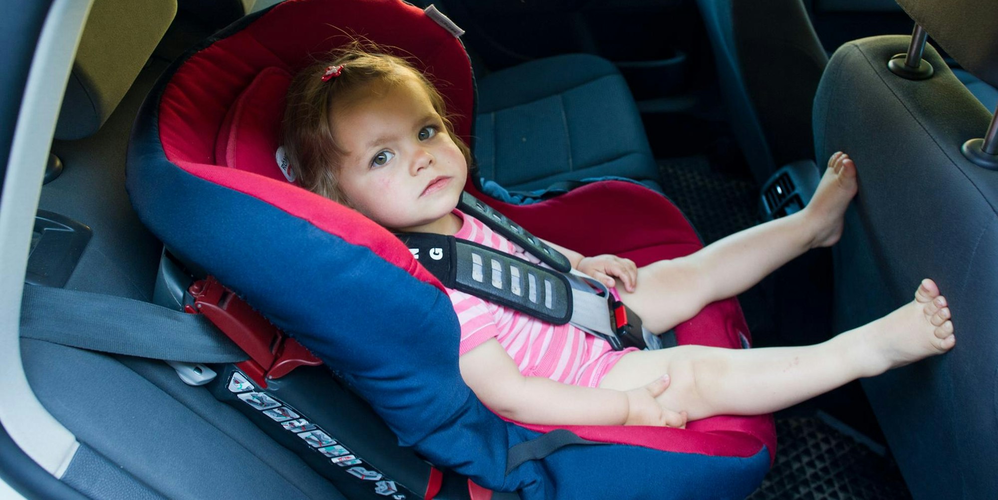 Kleinkind sitzt in einem Autokindersitz.