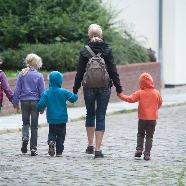 Das Foto zeigt eine Frau und fünf Kinder, die sich an den Händen halten.