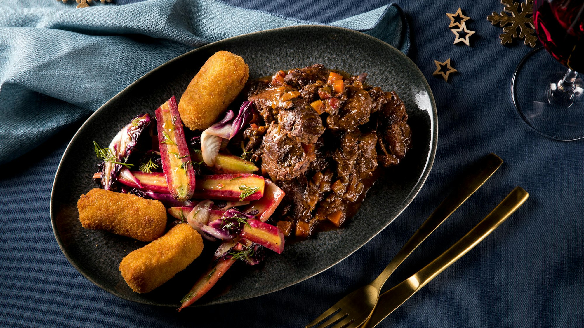 Saftiges Hirschgulasch mit bunten Möhren und Kroketten