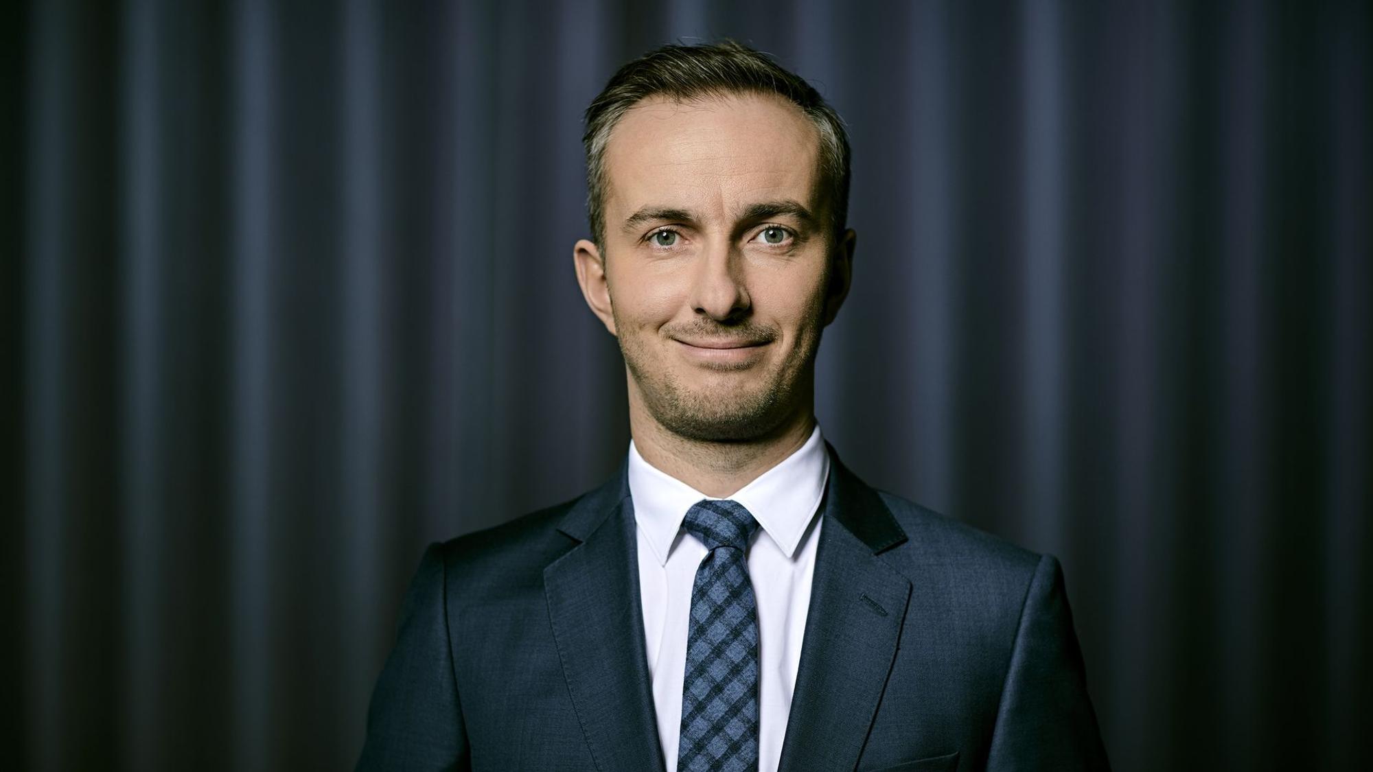 Jan Boehmermann vor einem grauen Vorhang.
