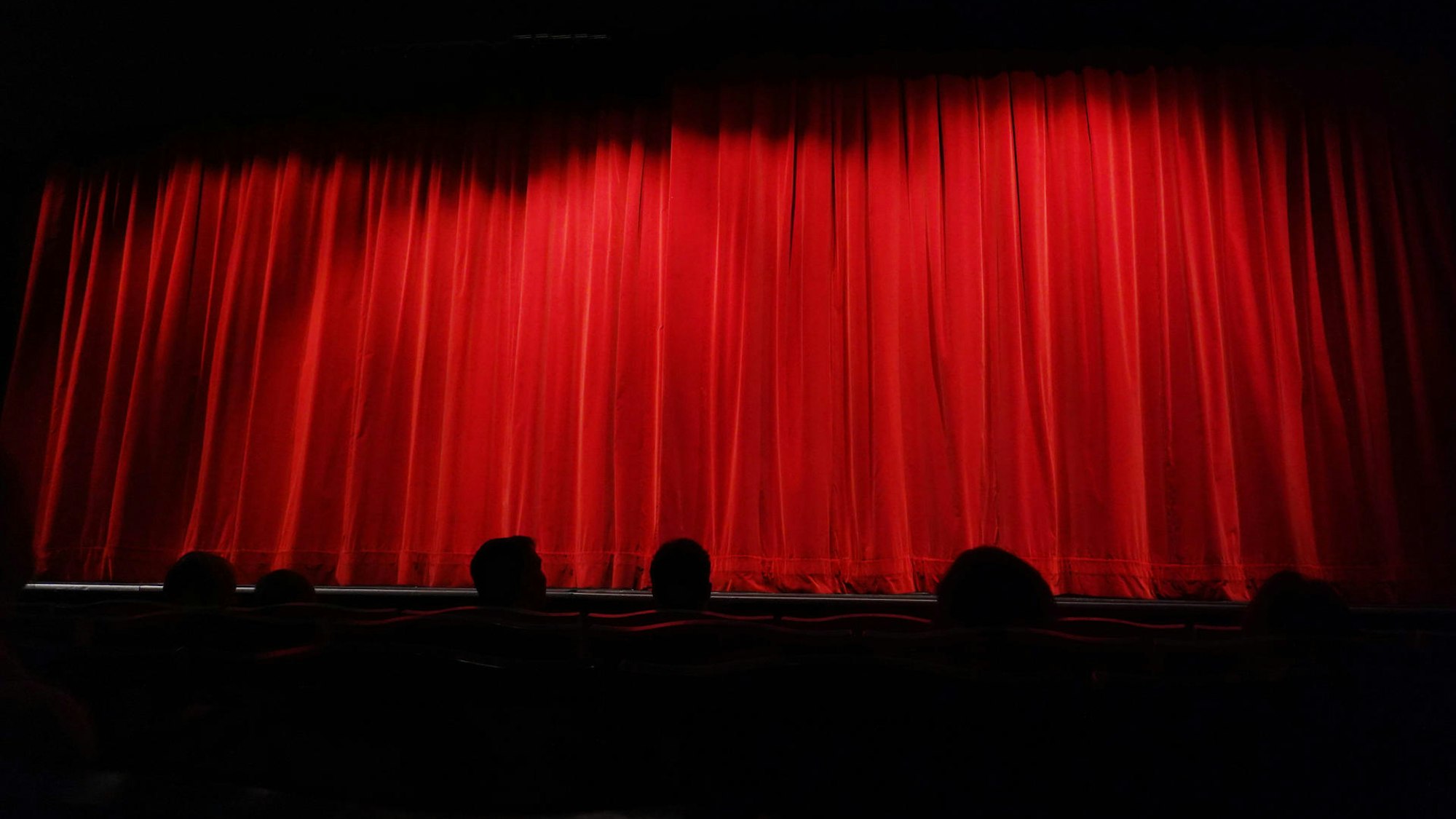 Ein roter Kinovorhang vor einer Leinwand.