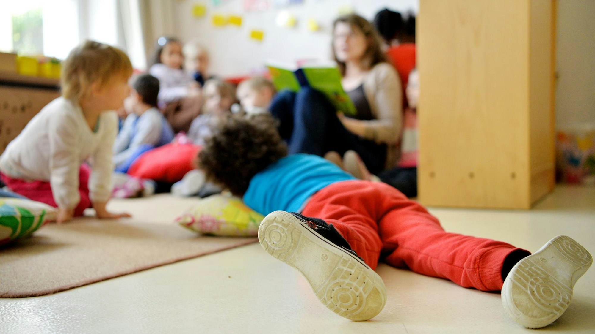 Kinder bekommen in einer Kita ein Buch vorgelesen.