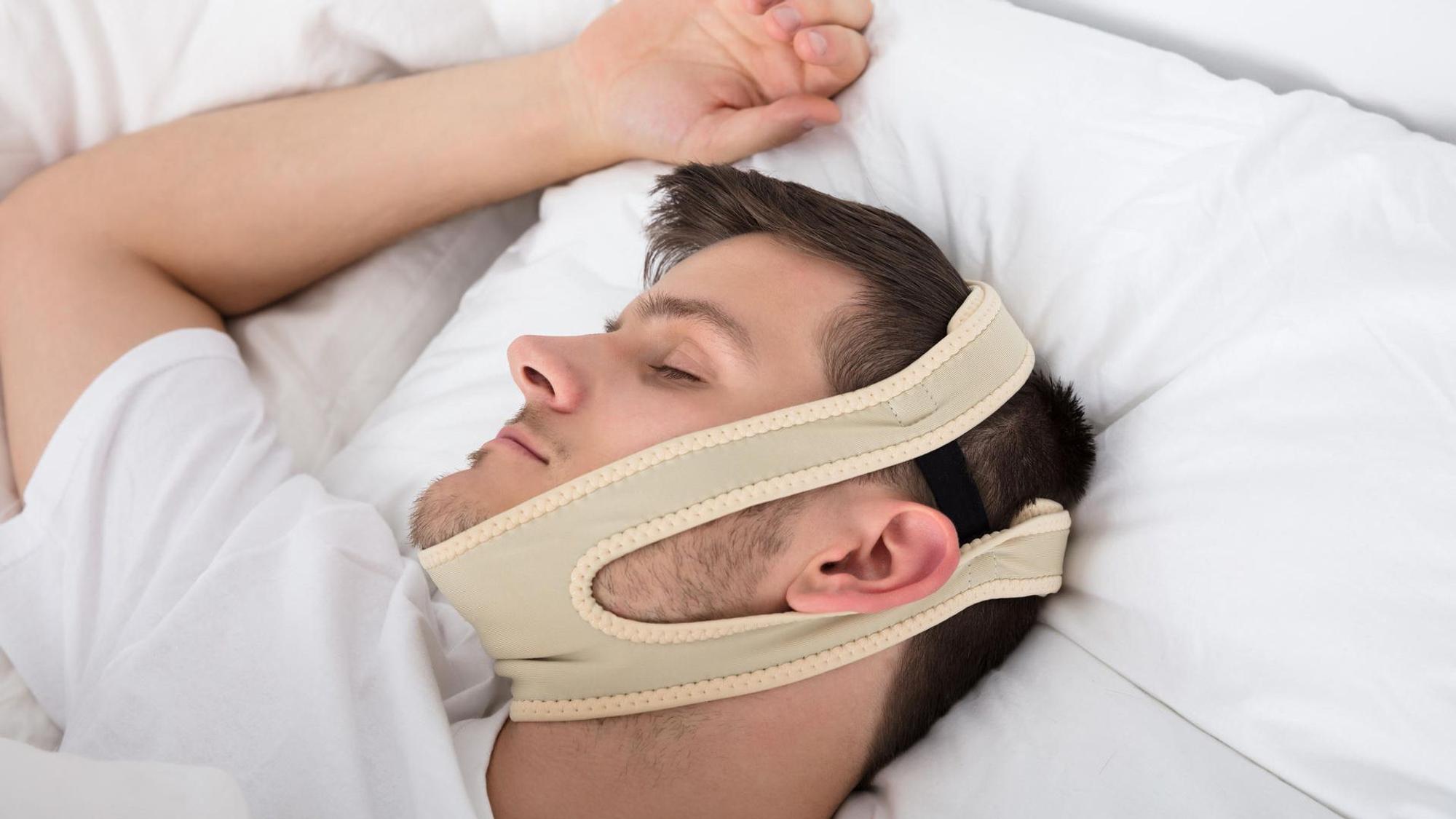 Mann liegt im Bett mit Schnarchband.