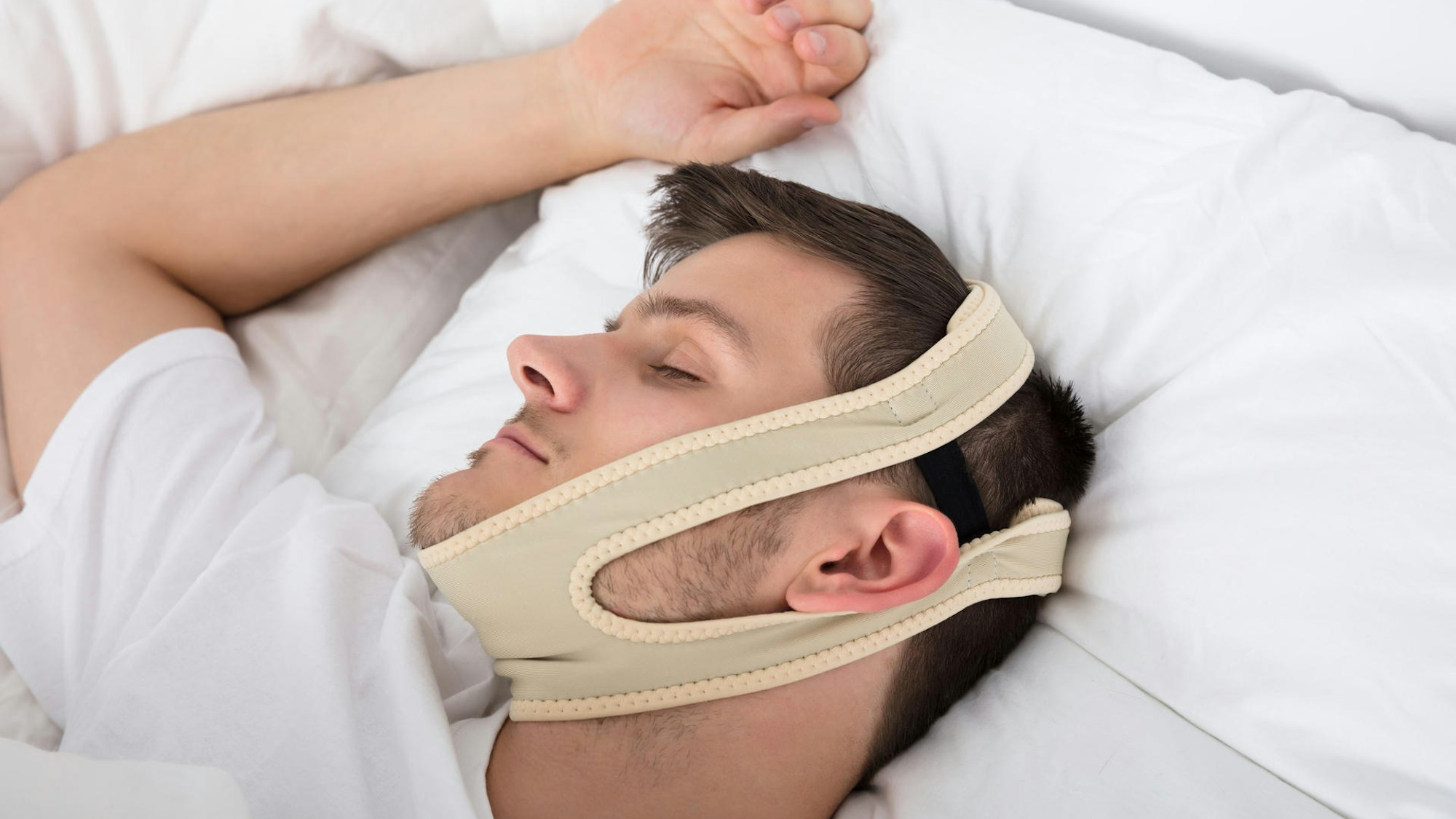 Mann liegt im Bett mit Schnarchband.