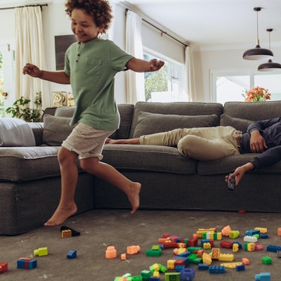 Ein Junge rennt durchs Wohnzimmer, während der Vater auf der Couch liegt.