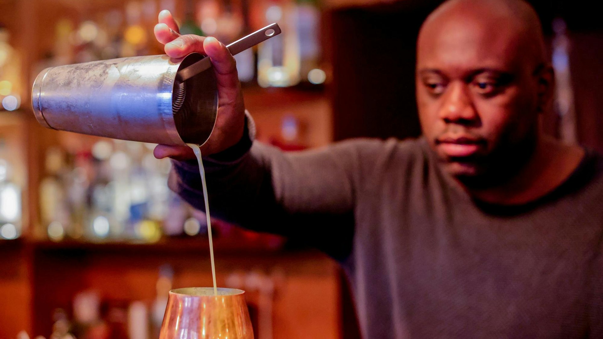 Barchef Samuel Antonio-Bernardo gießt Flüssigkeit in ein Cocktailglas.