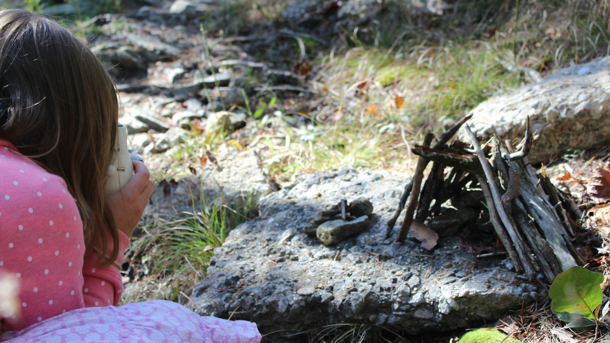 Mädchen fotografiert ein selbstgebasteltes Häuschen aus Zweigen