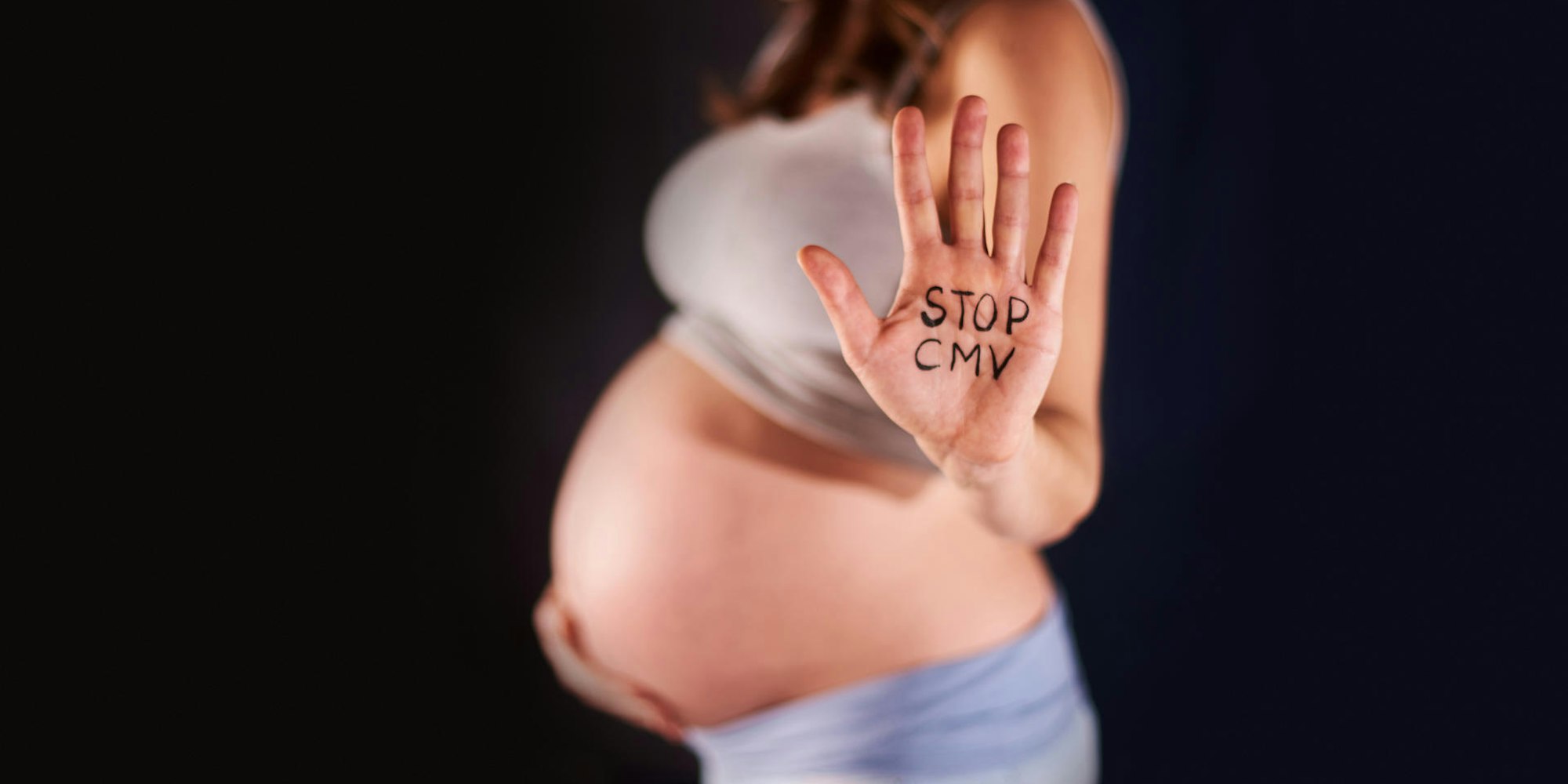 Hand einer Schwangeren mit dem Schriftzug "Stopp CMV"