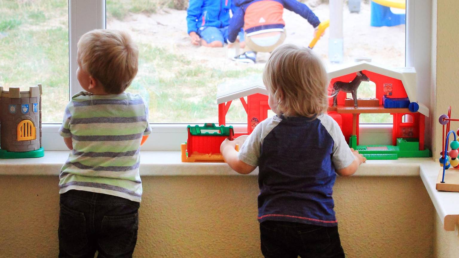 Zwei Kinder gucken in der Kita aus dem Fenster