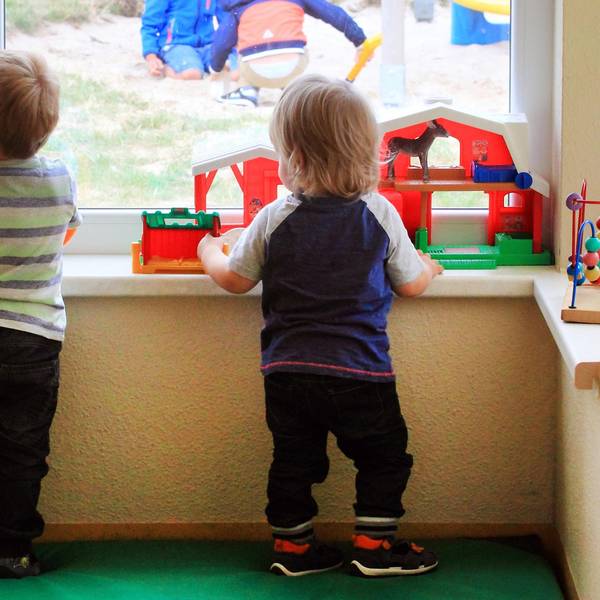 Zwei Kinder gucken in der Kita aus dem Fenster