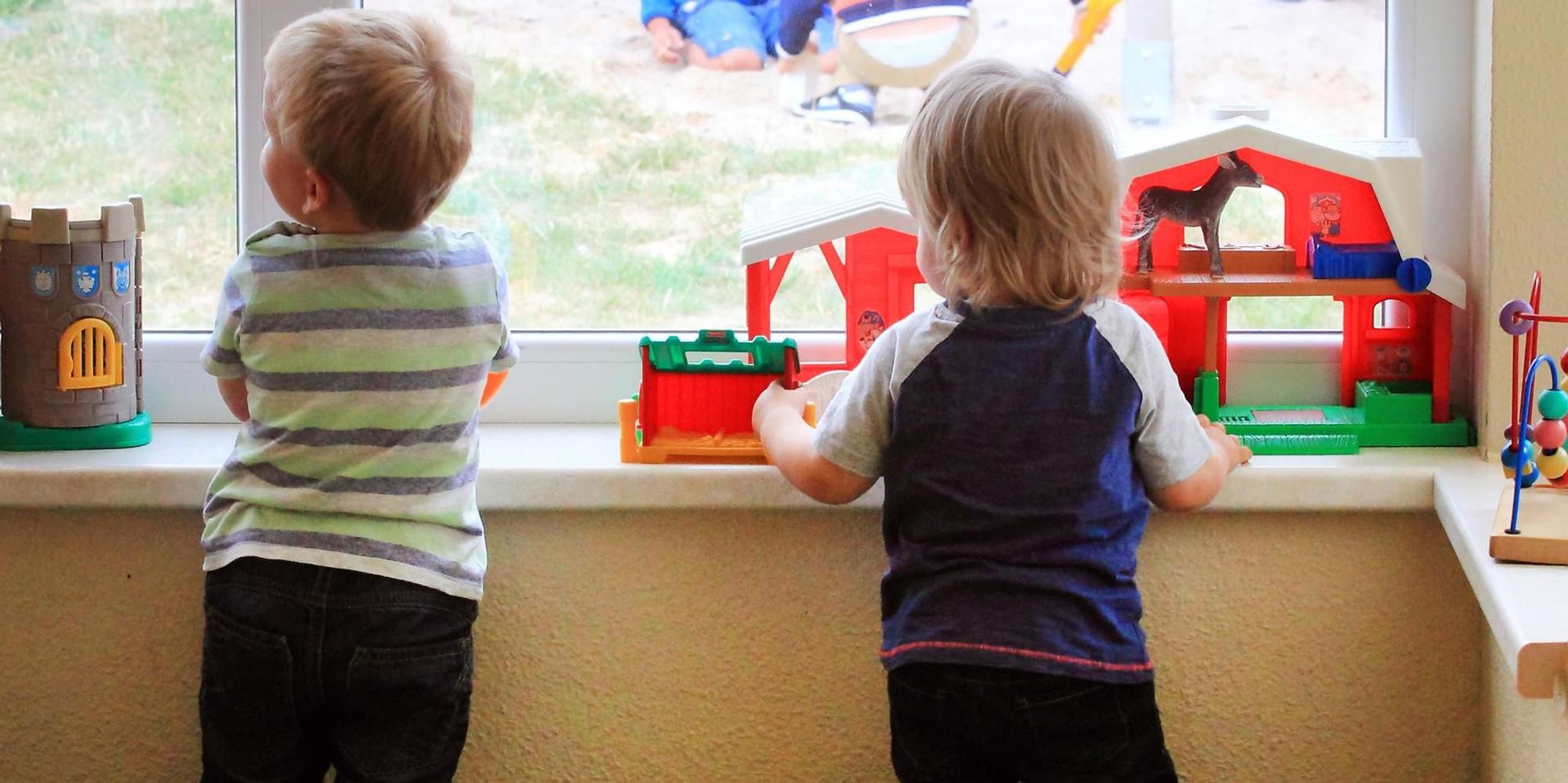 Zwei Kinder gucken in der Kita aus dem Fenster