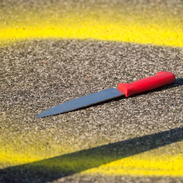 Ein Kreis aus gelber Farbe ist um ein Messer, das auf einer Straße liegt, gemalt.