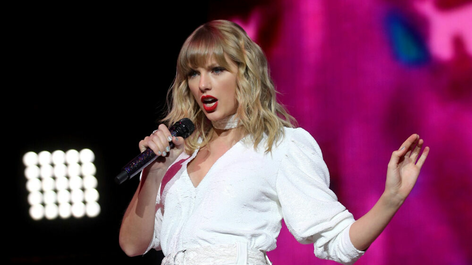 Sängerin Taylor Swift steht auf der Bühne und singt in ein Mikrofon.