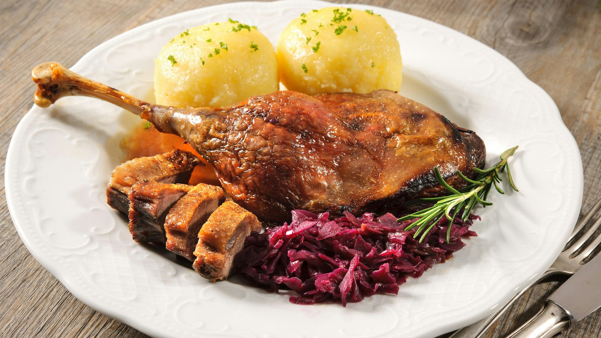 Gänsekeule mit Beilagen auf einem Teller.