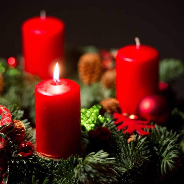 Eine Kerze brennt an einem Adventskranz