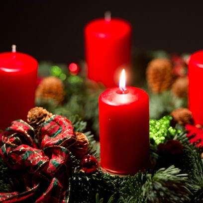 Eine Kerze brennt an einem Adventskranz