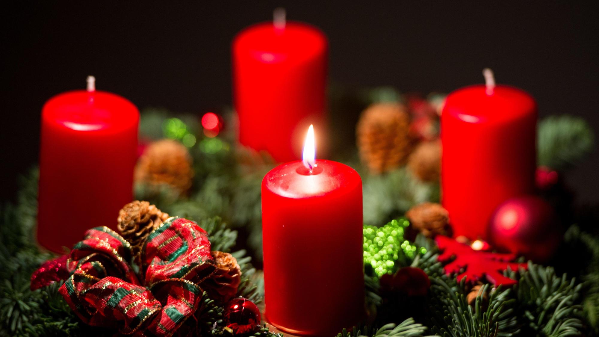 Eine Kerze brennt an einem Adventskranz