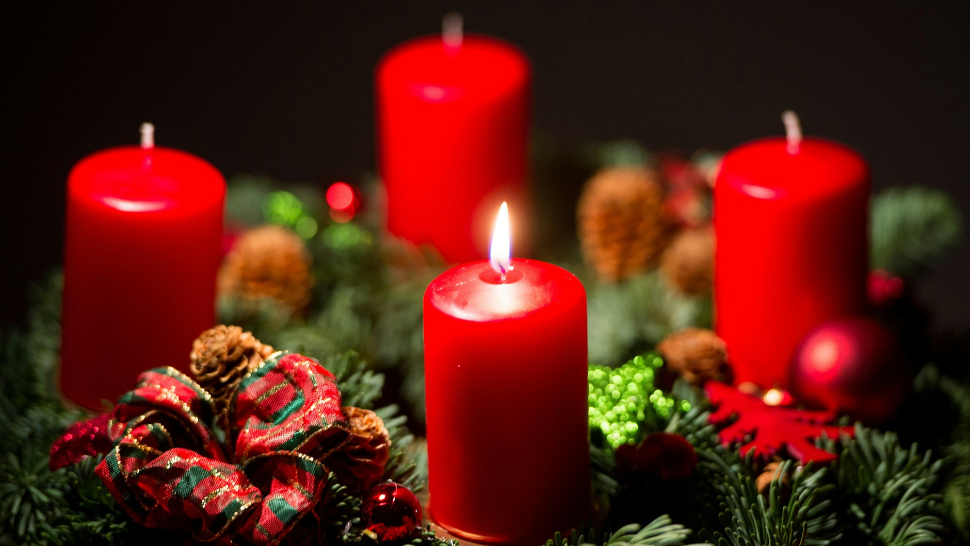 Eine Kerze brennt an einem Adventskranz