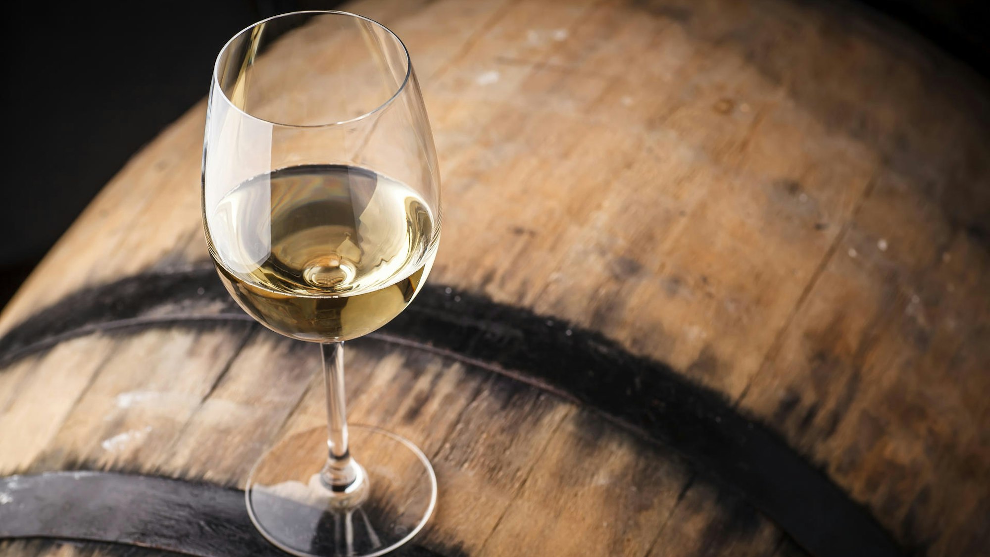 Ein Weinglas steht auf einem Fass