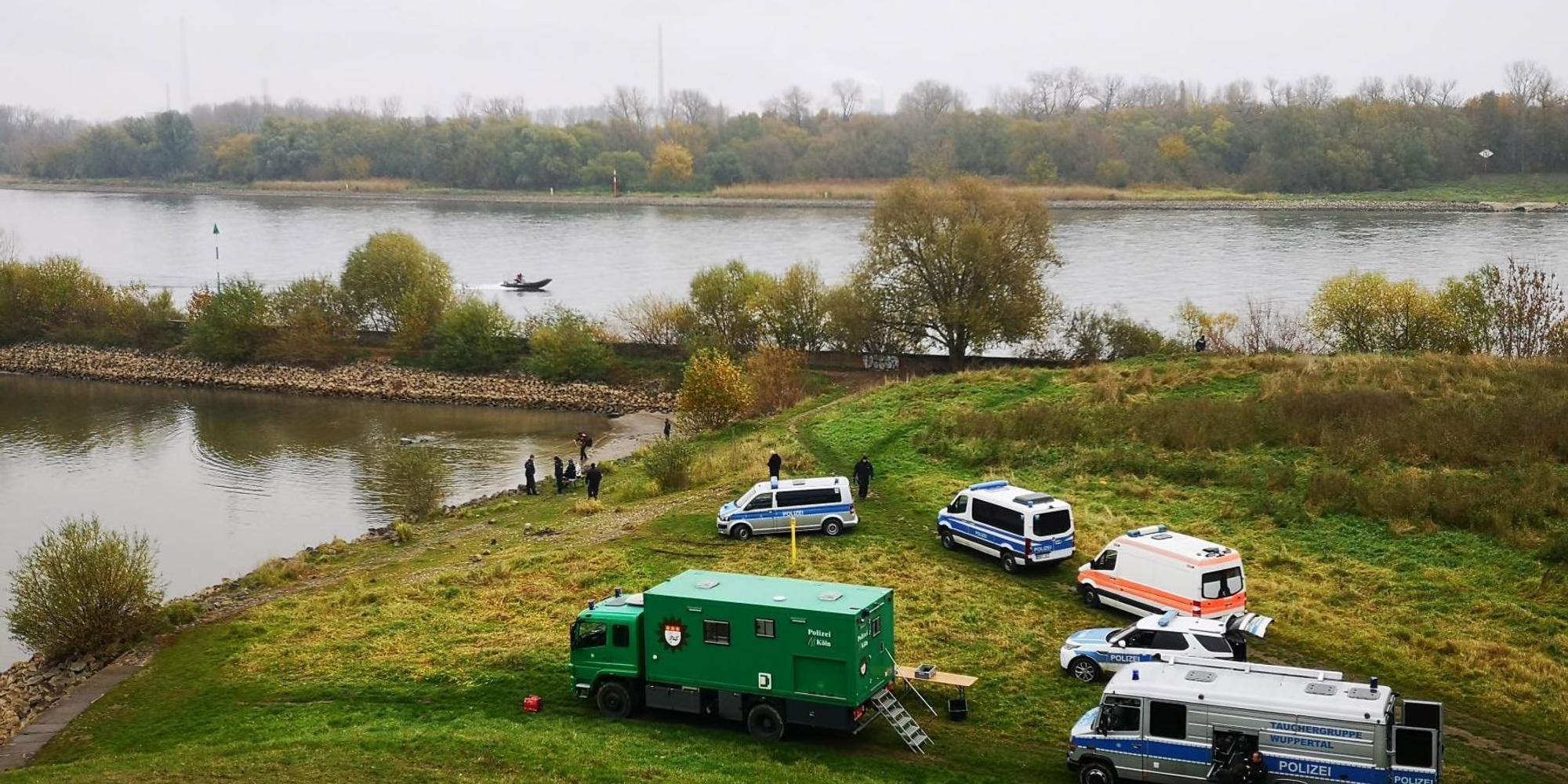 Autos der Polizei auf einer Wiese am Ufer am Niehler Hafen