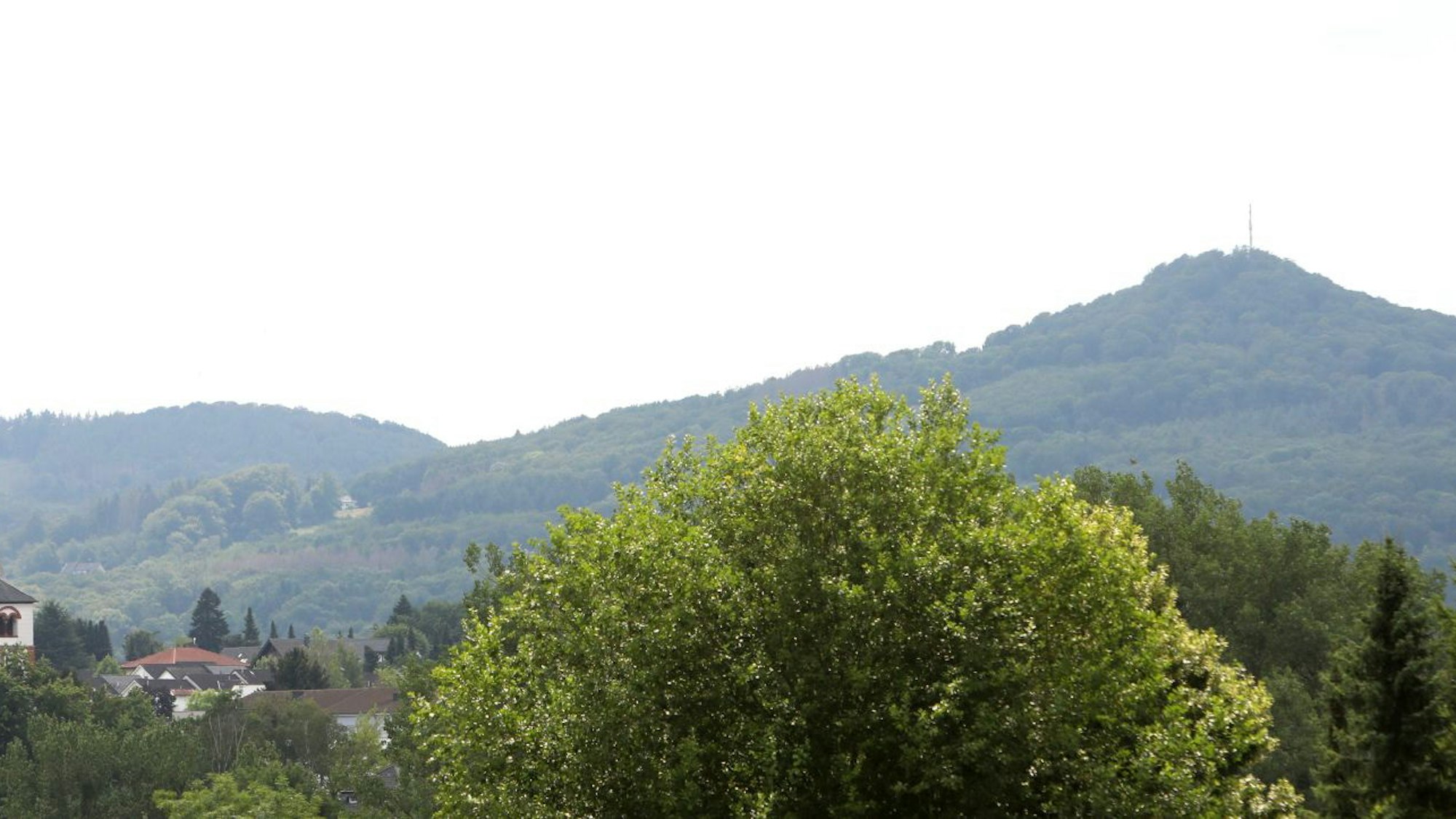 Auf dem Foto ist ein Kirchturm vor Bergwipfeln zu sehen.