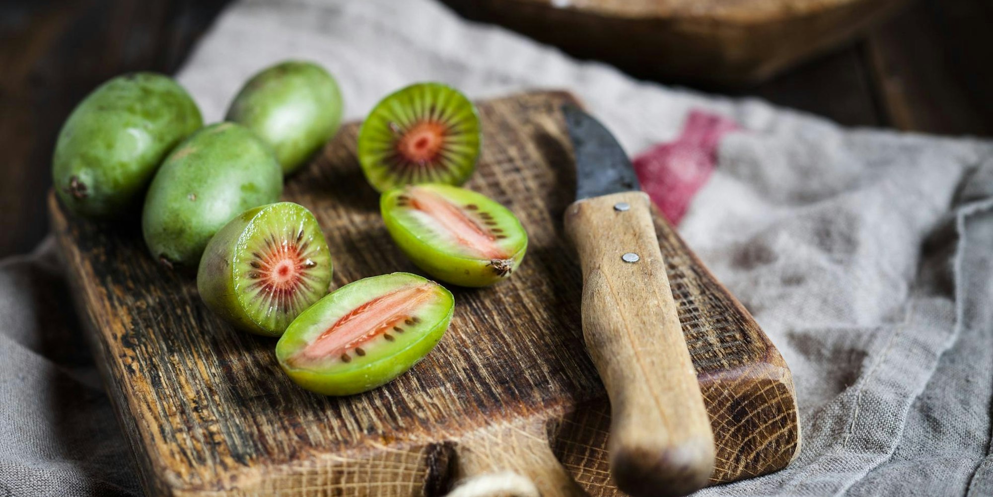 Minikiwis liegen angeschnitten auf einem Brettchen