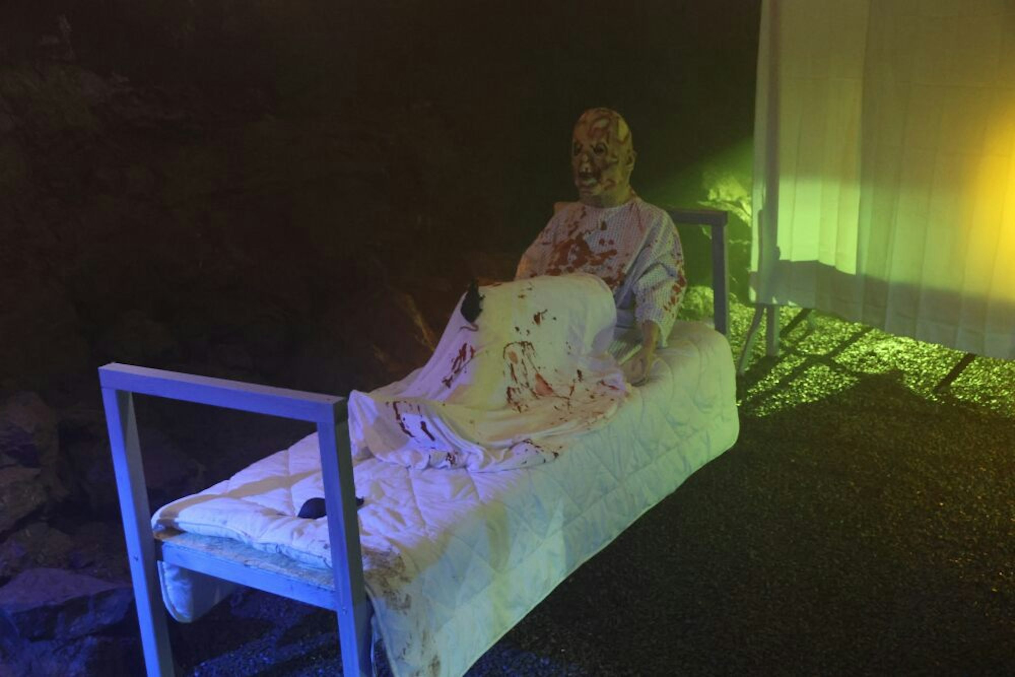 Ein Mann sitzt mit Kunstblut beschmiert in einem Bett.