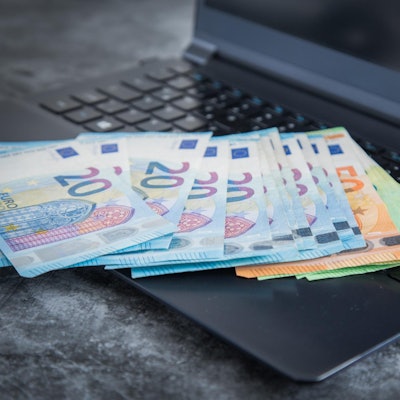 Verschiedene Euro-Scheine liegen auf einem Laptop.