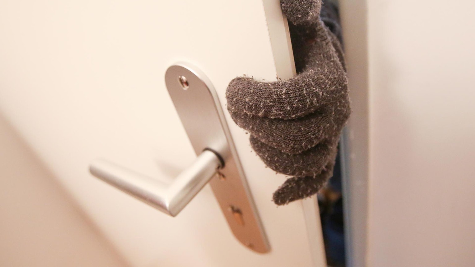 Dieb Einbrecher an Tür nur Handschuh zu sehen