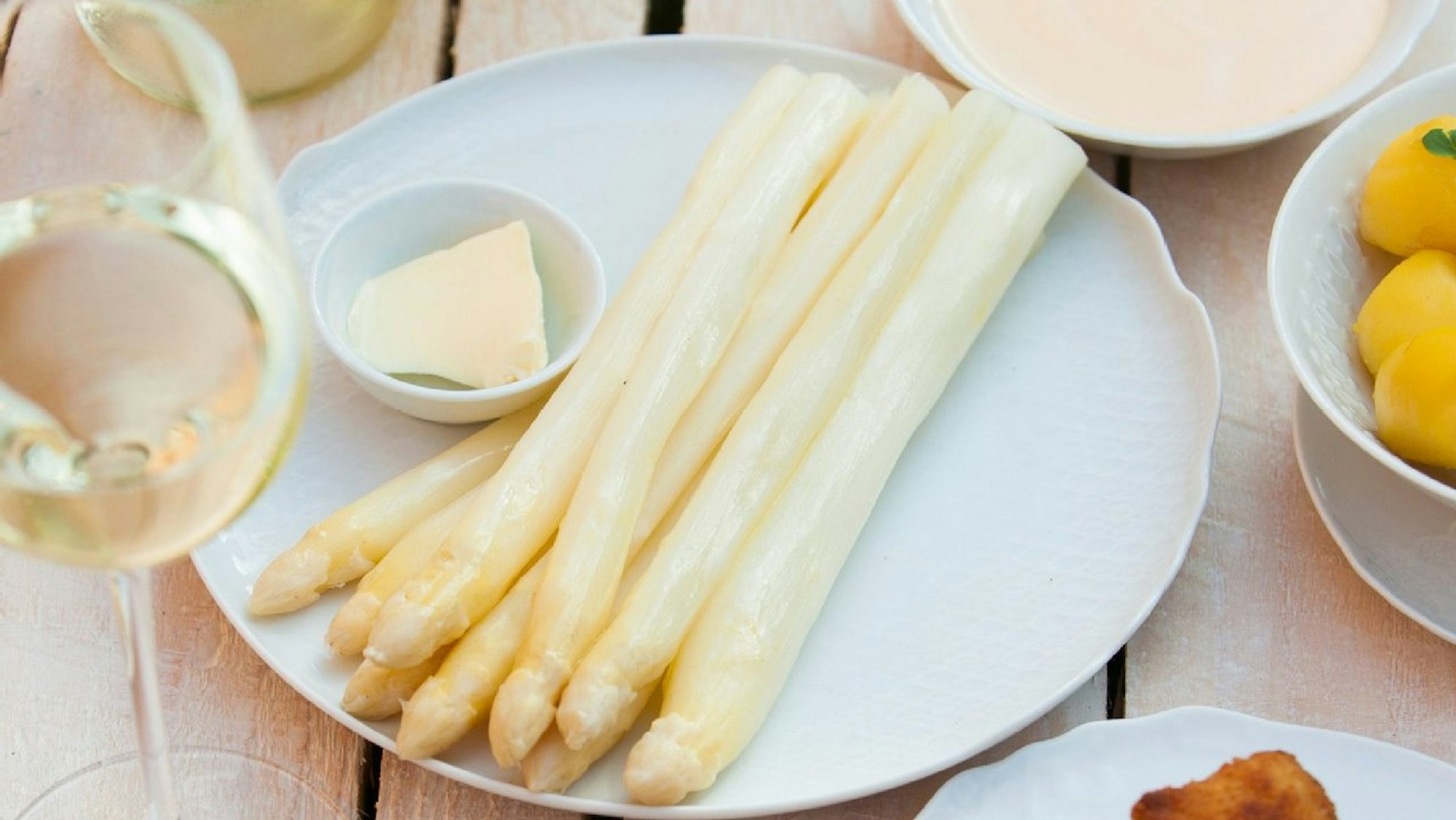 Spargel mit Weißweinsauce, Hollandaise und Schnitzel oder Schinken, auf einem Teller.
