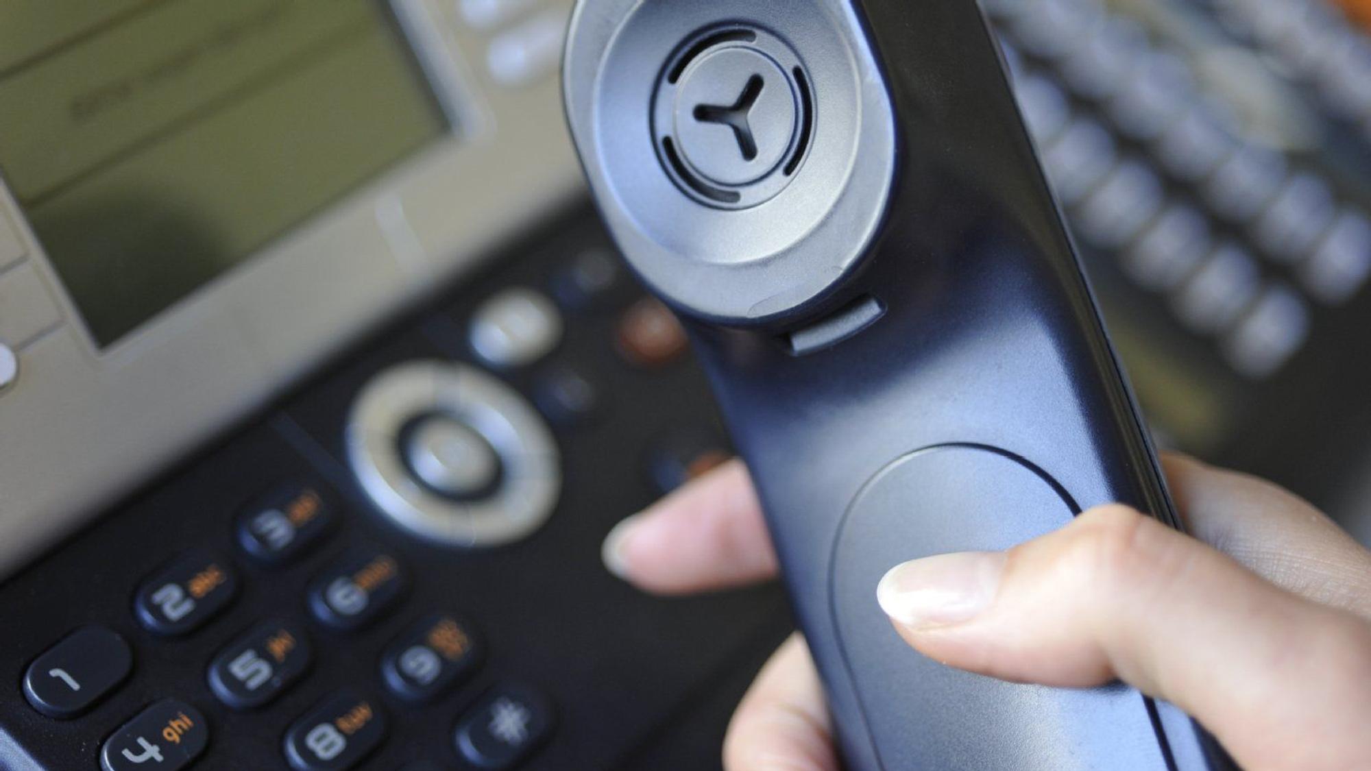 Ein Telefon und ein Telefonhörer in einer Hand.